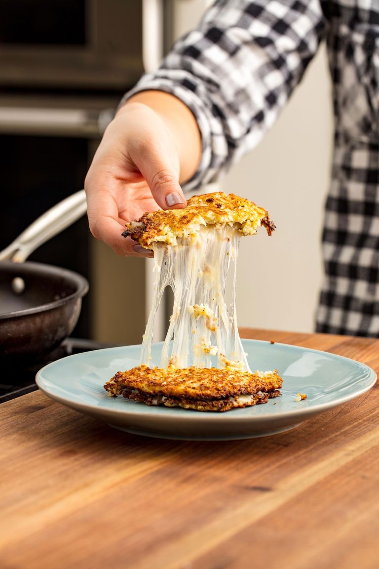 cauliflower grilled cheese on a plate with a cheese pull from man in a plaid shirt