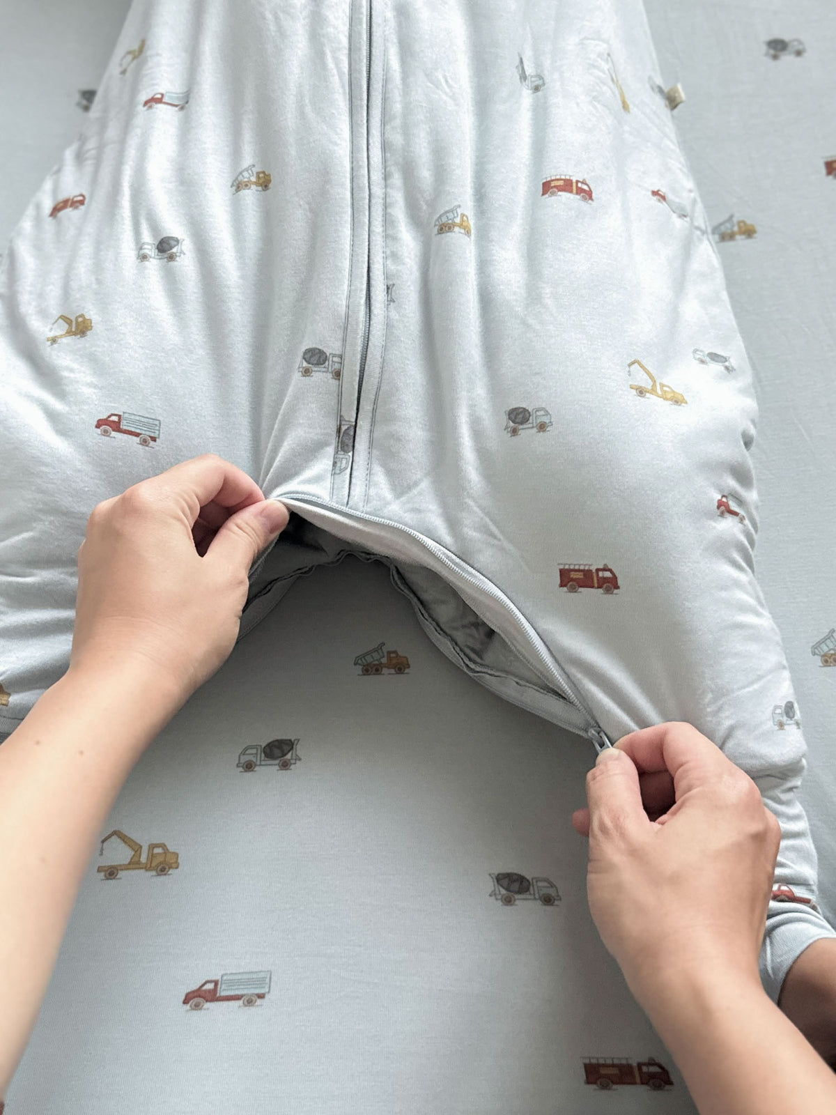 Light blue footie sleep sack with open zipper panel and vehicle print interior