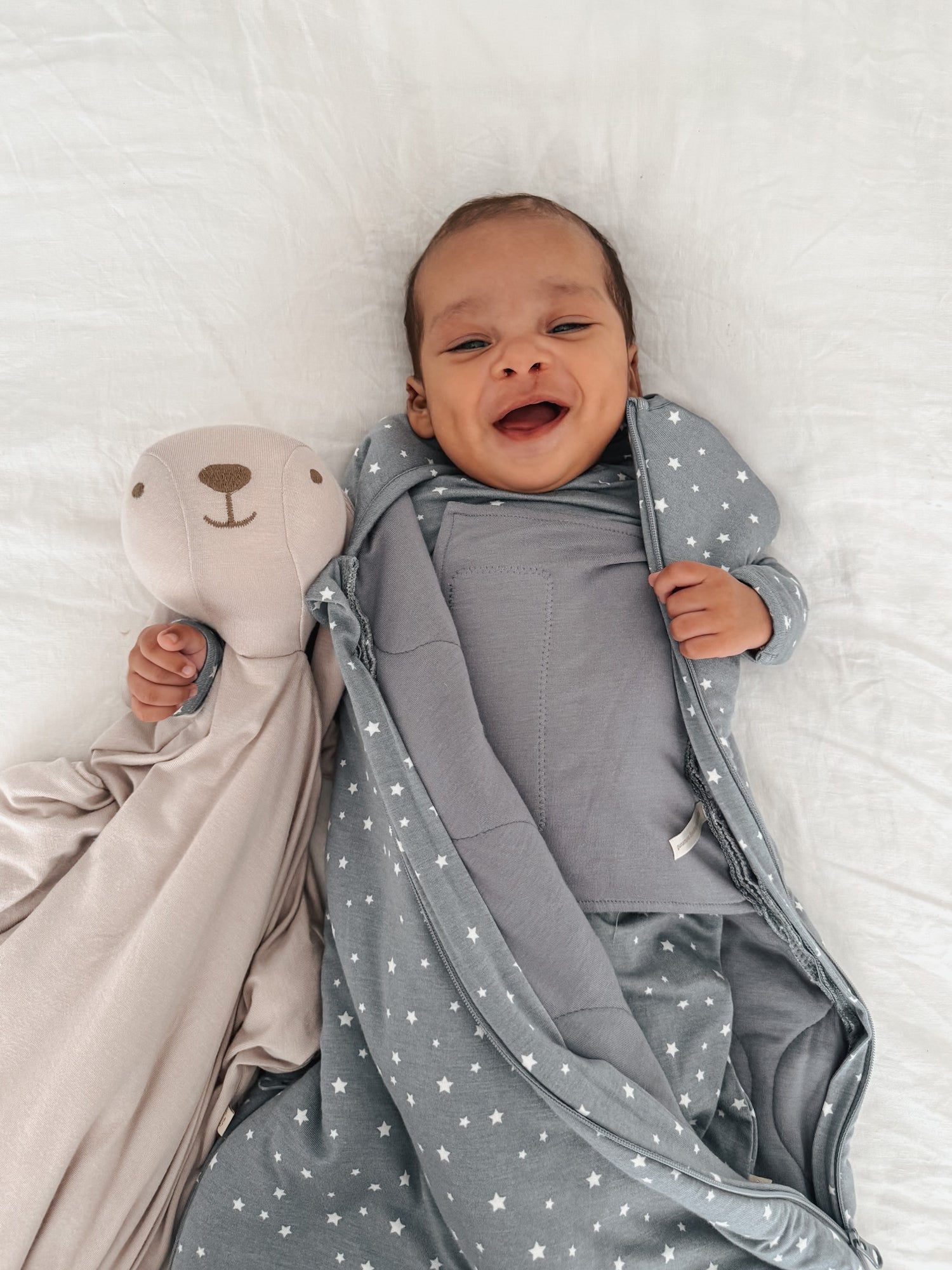 Gray swaddle sleep sack with white star print, baby wearing hooded wrap.