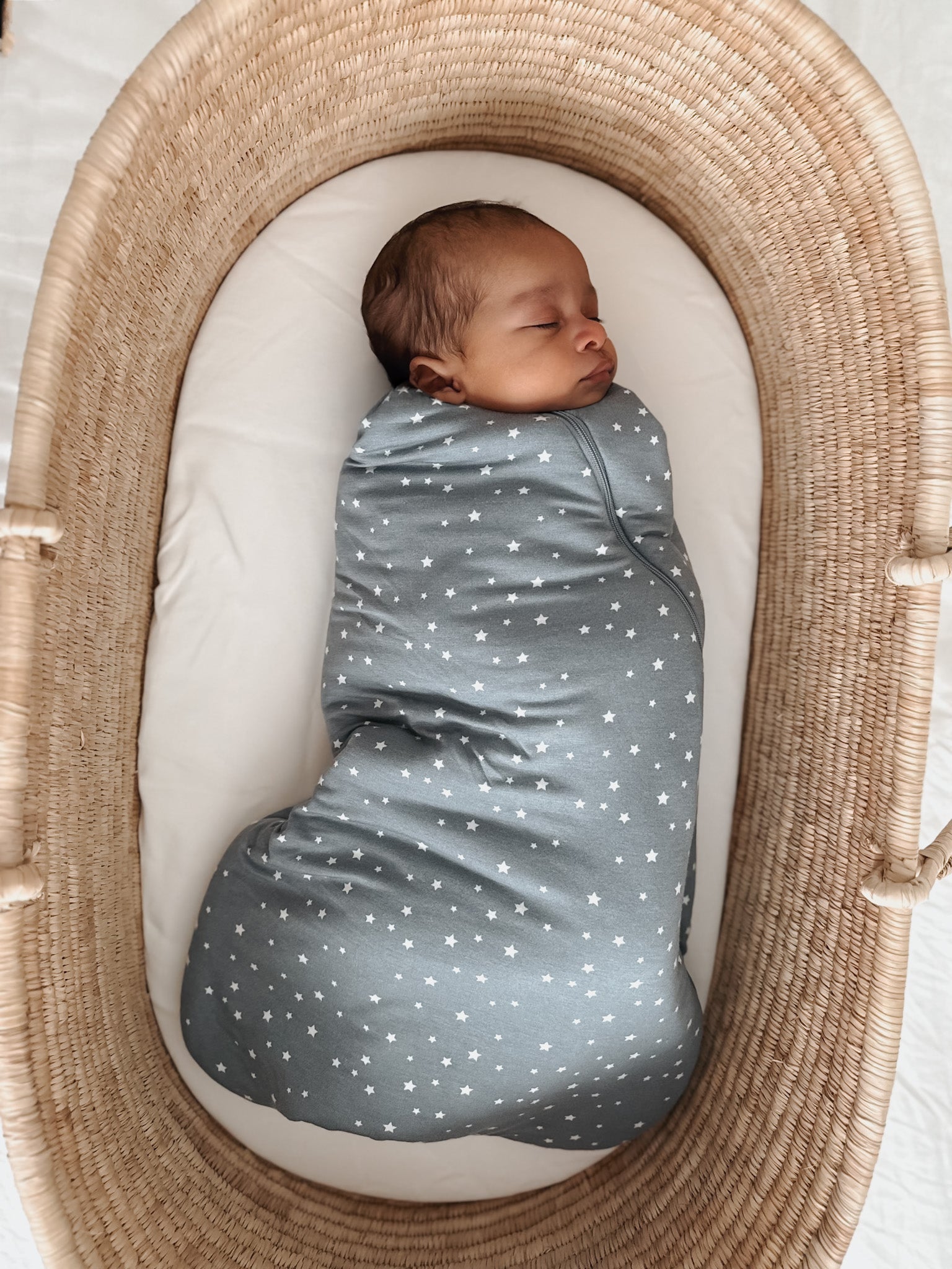 Gray star-print swaddle sleep sack with baby inside, sleeveless cocoon shape.