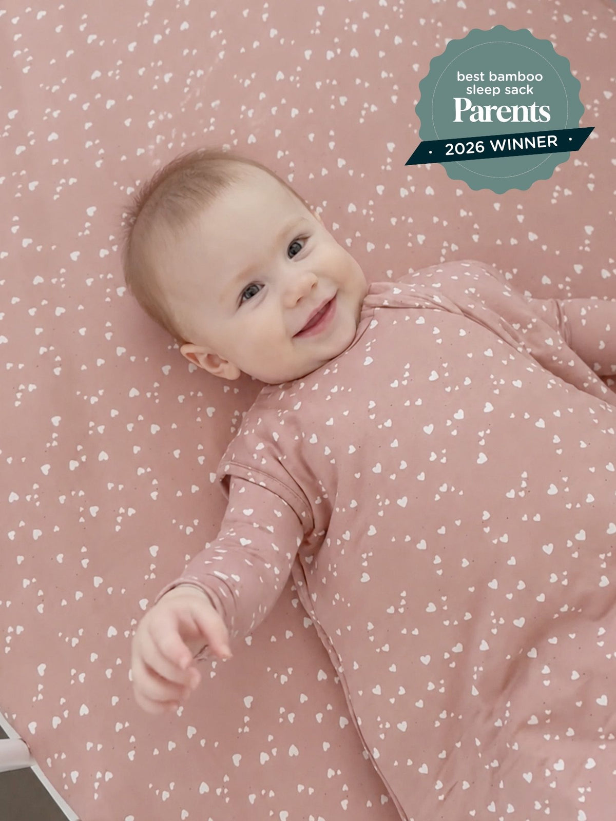 Baby sleep sack in blush pink with small heart pattern, long sleeves, front zip