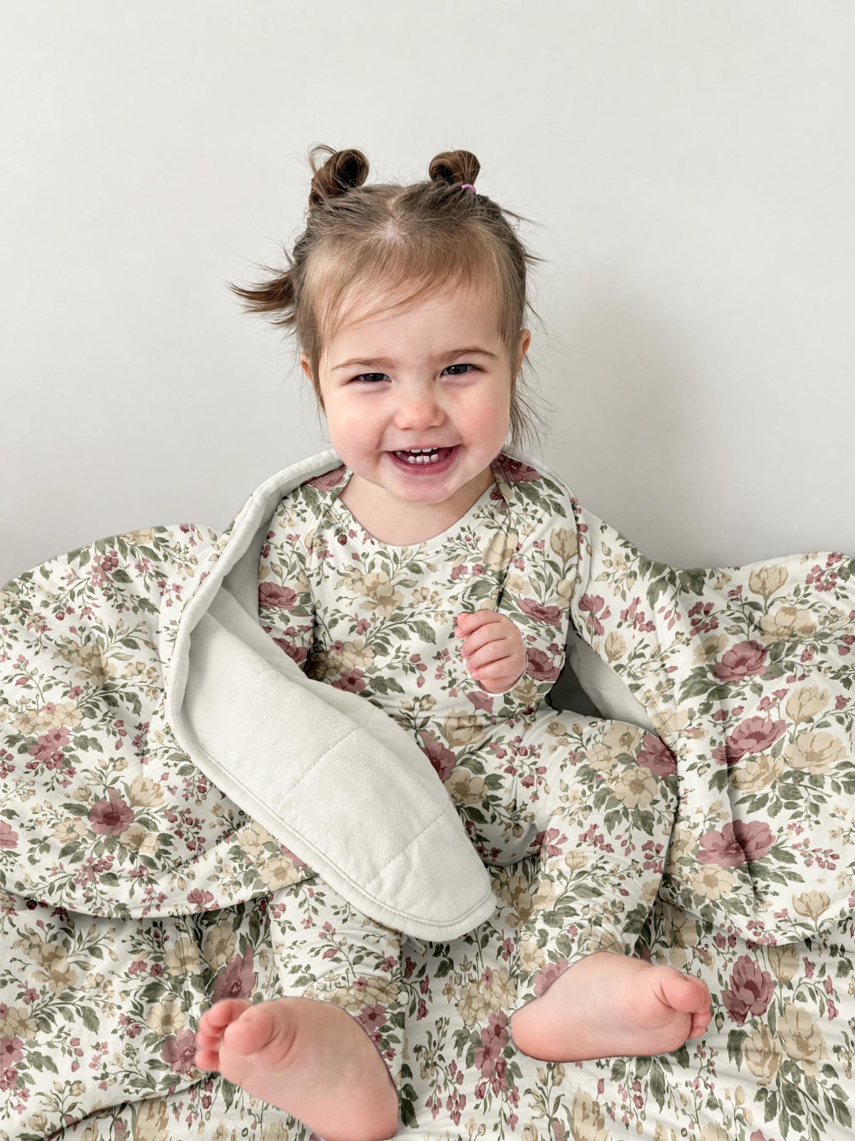 Beige floral cloud blanket with curved padded edge, folded and open