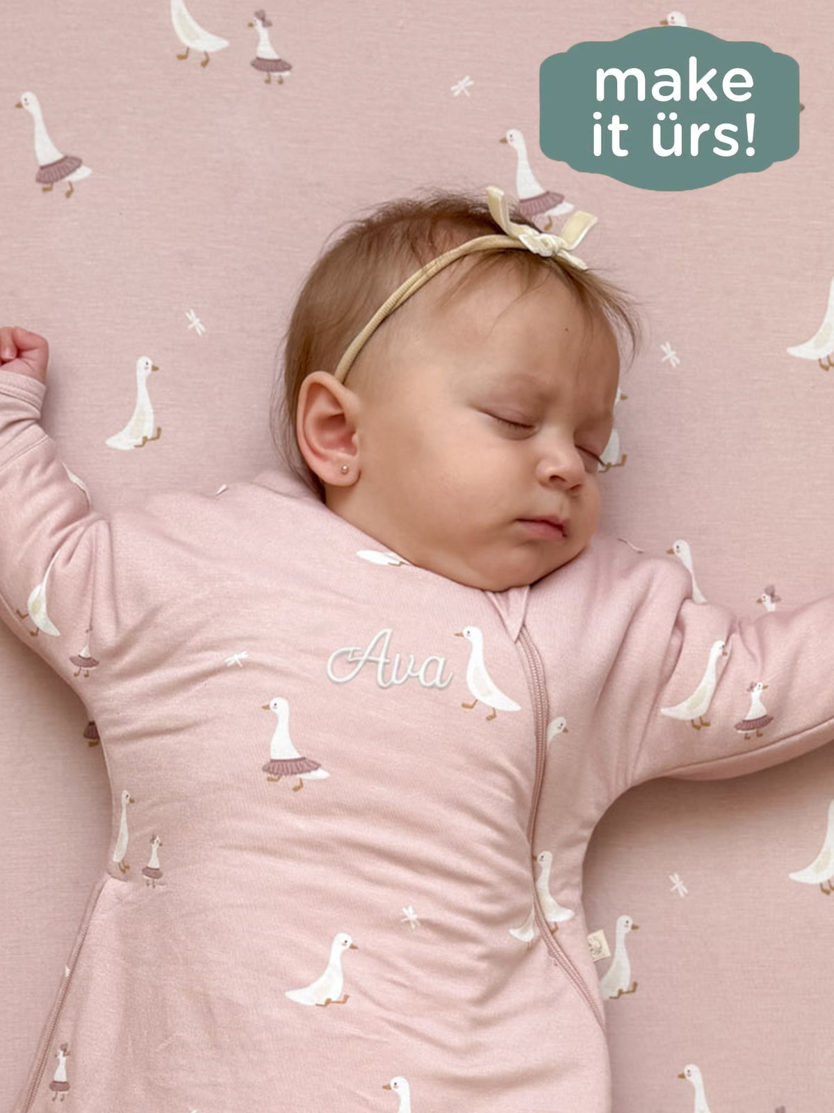Dusty pink swaddle sack with white goose print and folded cuff, baby lying