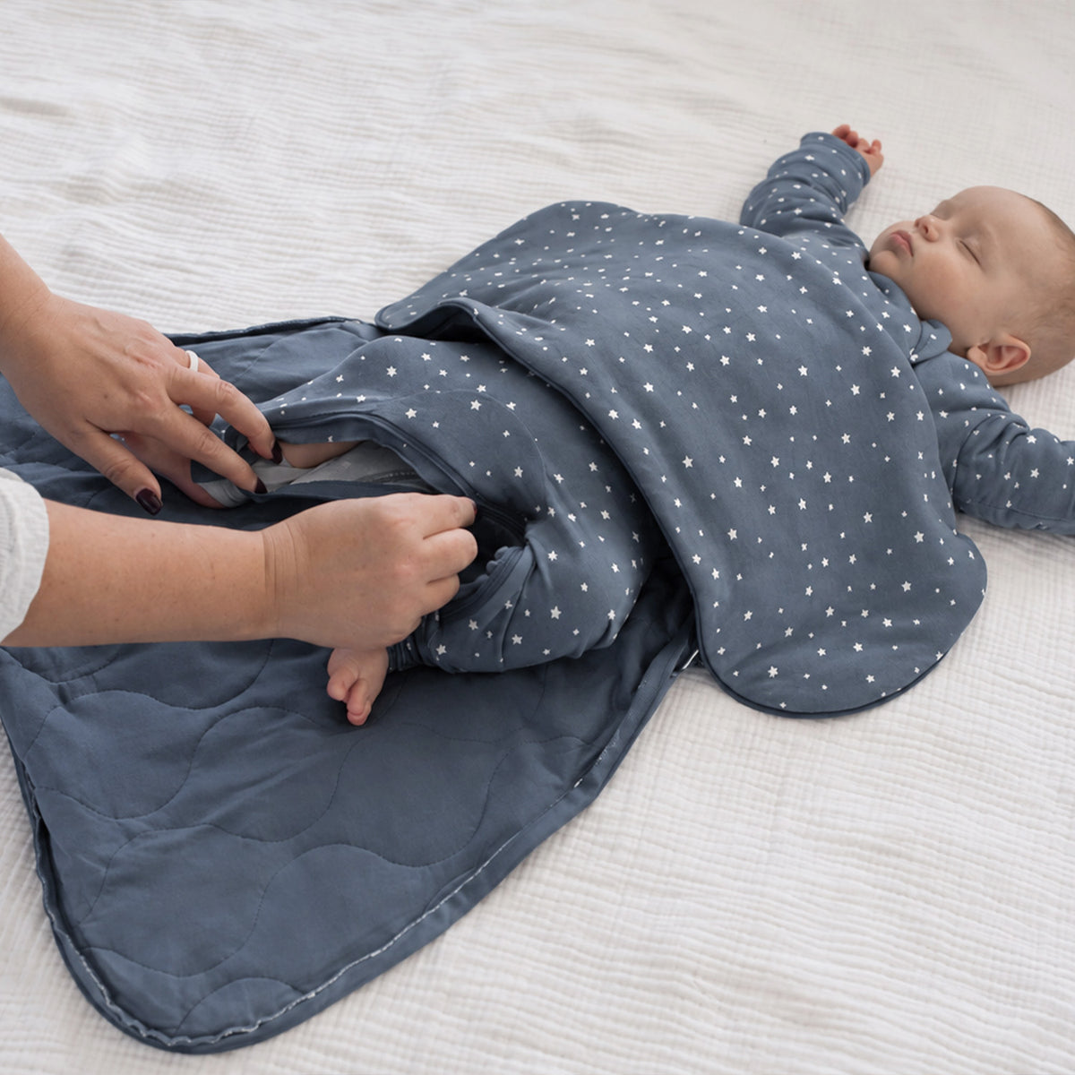 Long-sleeve sleep sack in slate blue with white stars, opened at the bottom for changing.