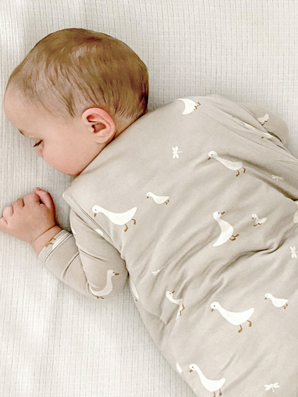 1.0 TOG goose print sleep sack, light gray; side view with baby inside