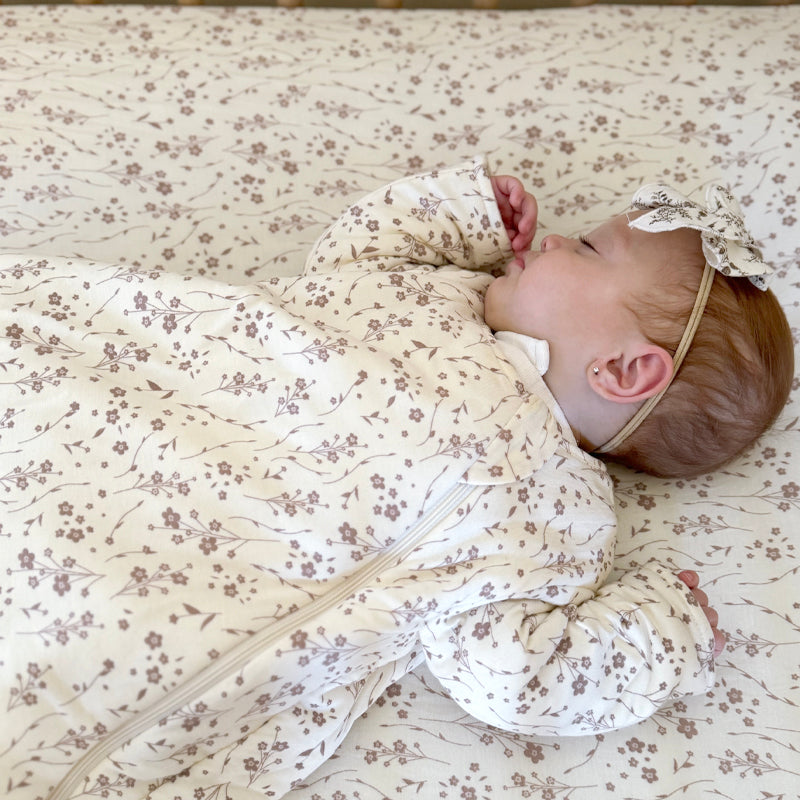 Cream floral long-sleeve sleep sack, baby lying on side with hands tucked