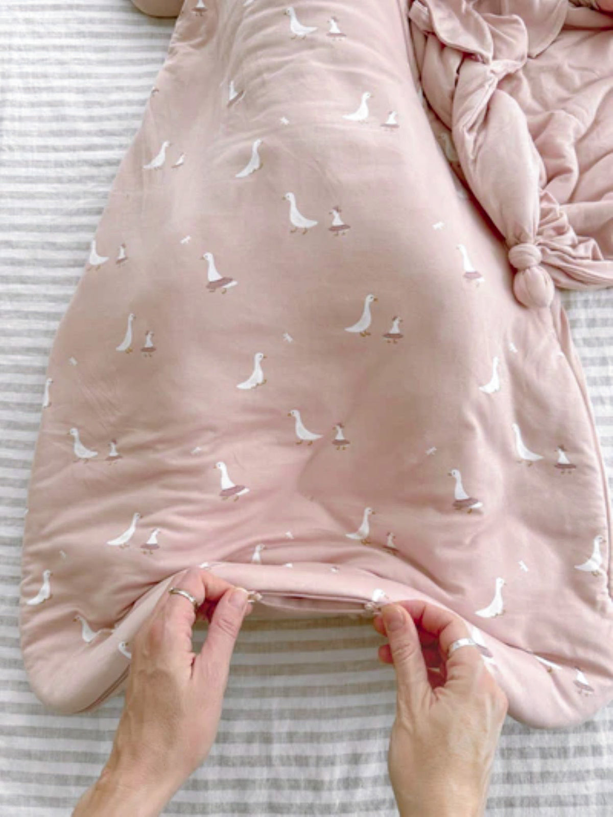 Pink 1.0 TOG sleep sack fabric close-up with scattered white goose silhouettes