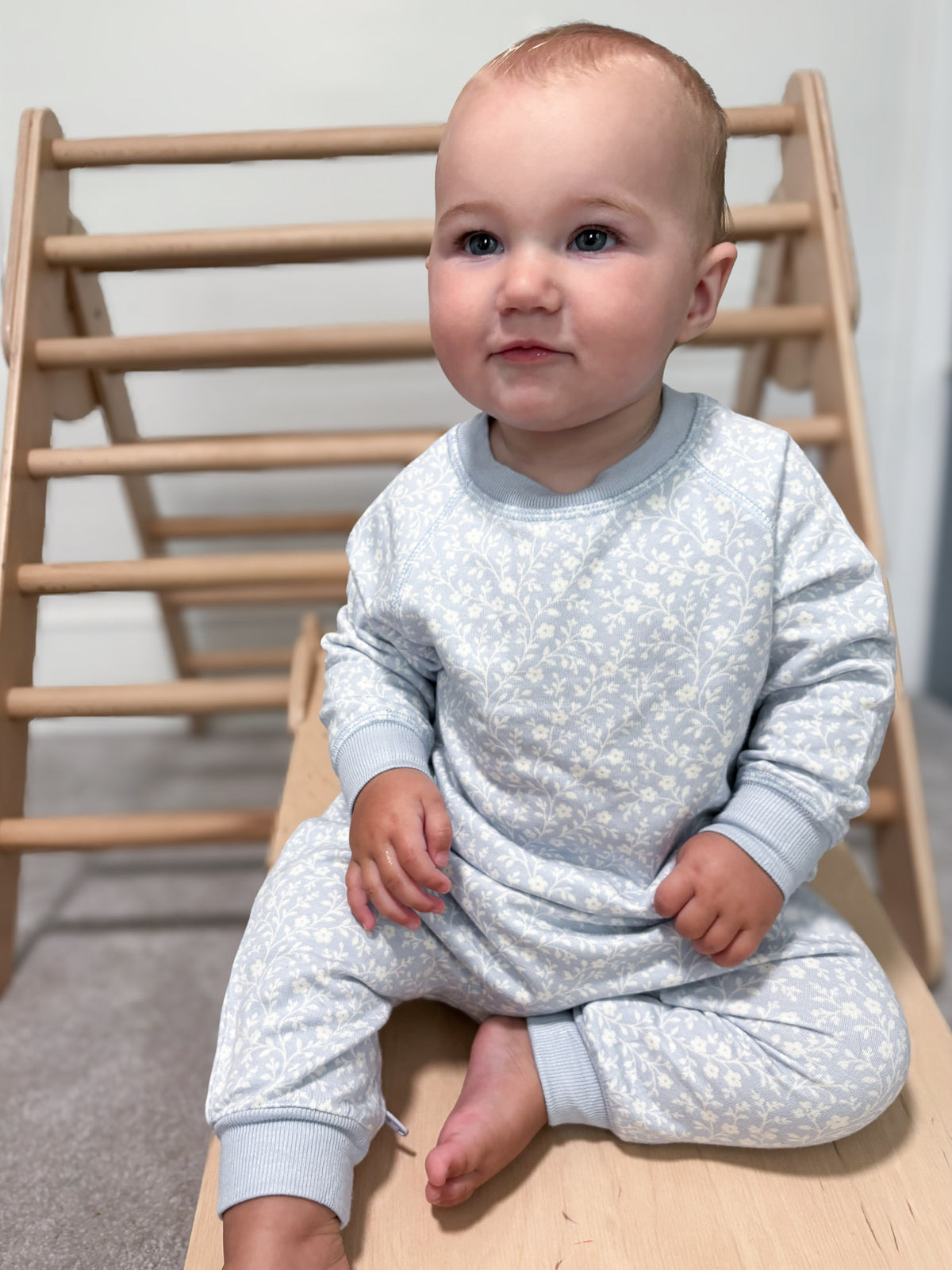 Light blue fleece jumpsuit with white floral print, long sleeves, and full-length cuffs