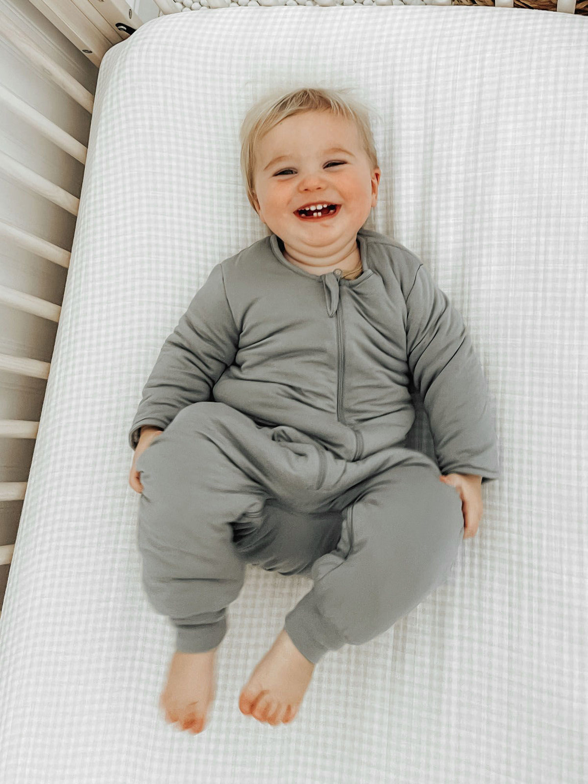 Sage green long-sleeve footie sleep sack lying pose, front zipper detail