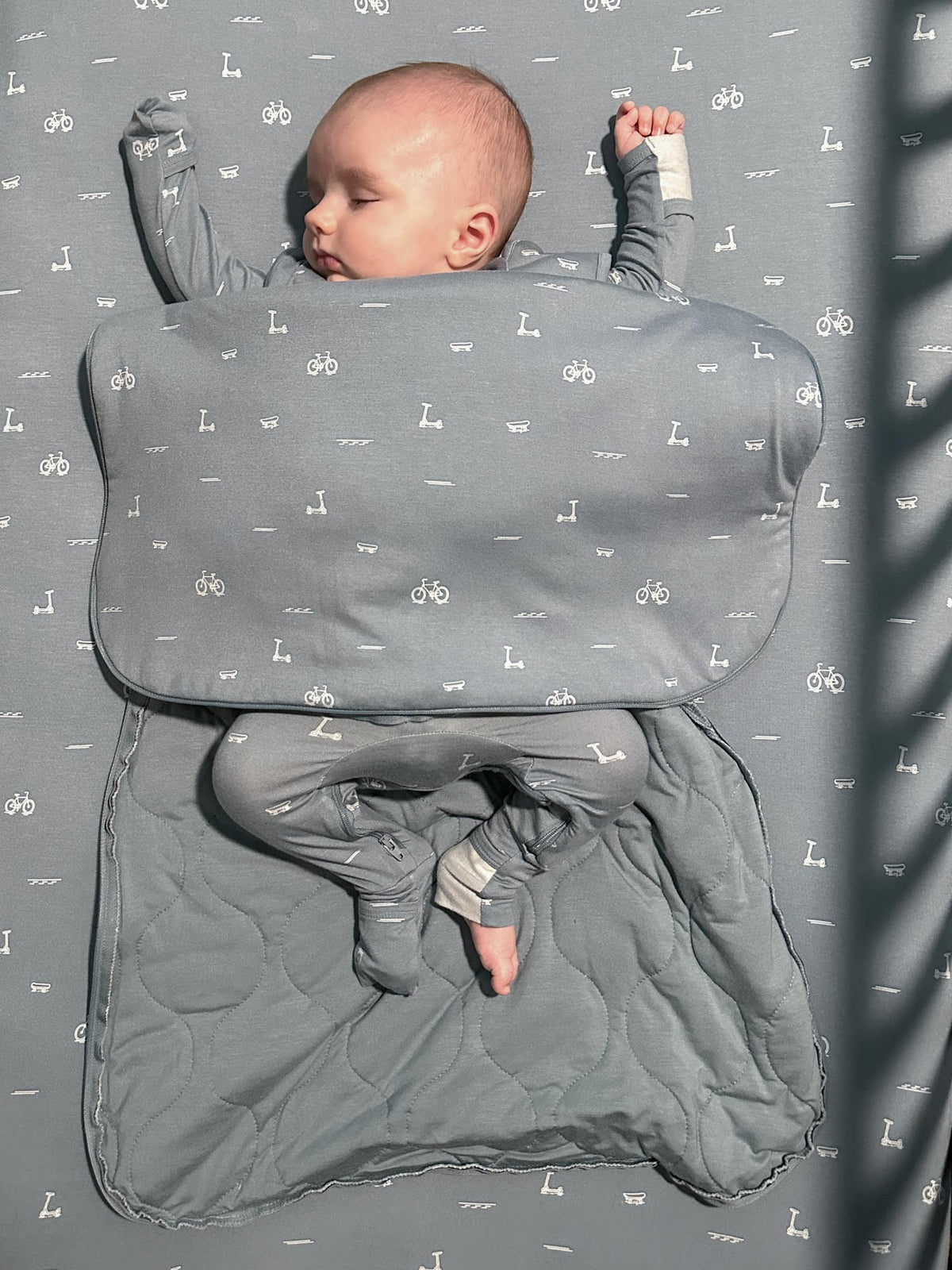 Grey 1.0 TOG sleep sack with icon pattern, baby lying inside