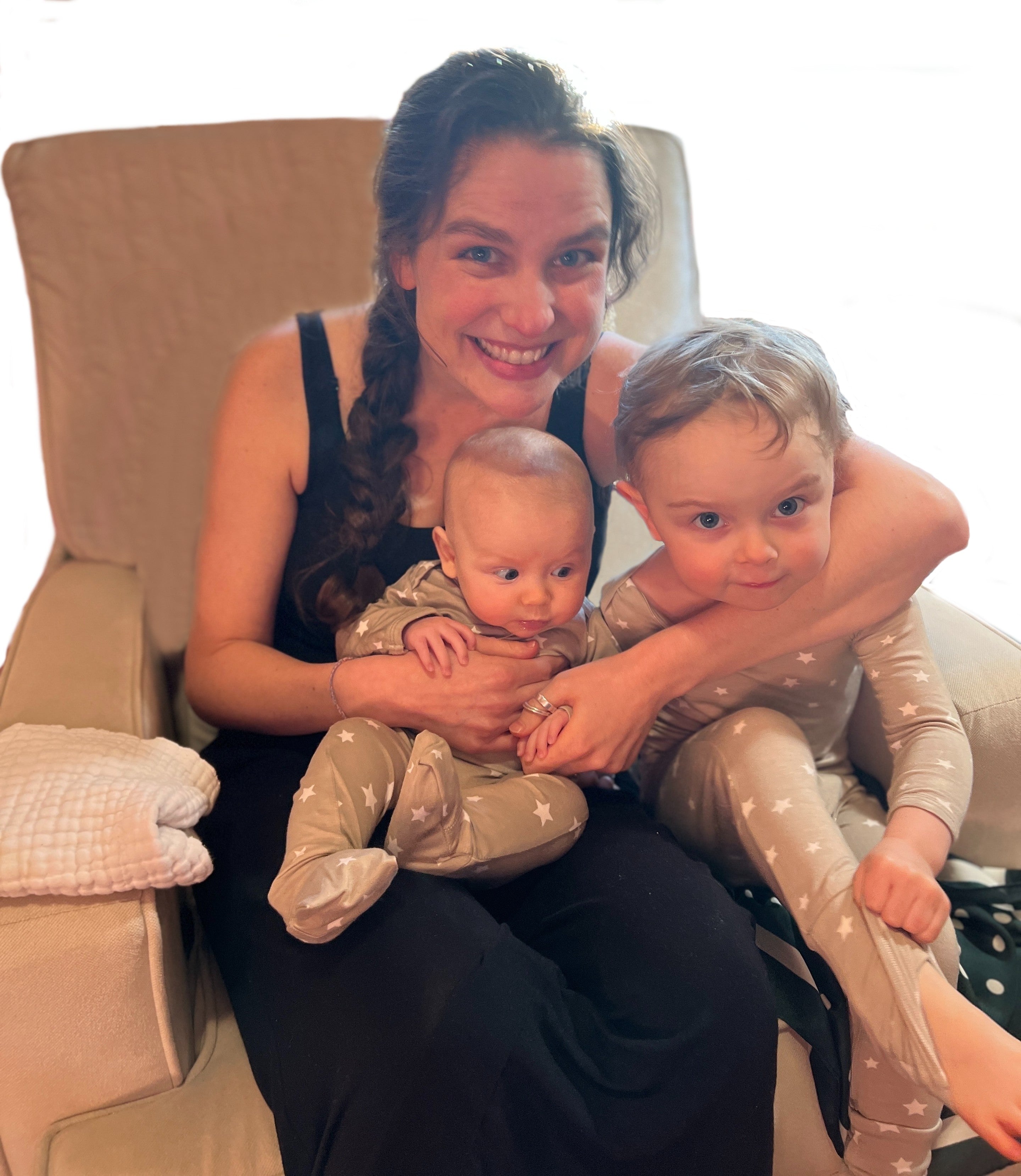 two children in matching gunamuna star printed convertible pajamas on their mother's lap