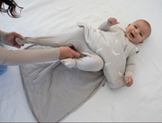 smiling baby with unzipped neutral goose printed sleep sack getting changed by his mom