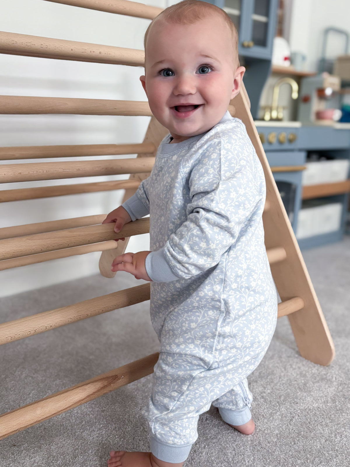 Light blue fleece jumpsuit with white floral print, long sleeves, and cuffed legs