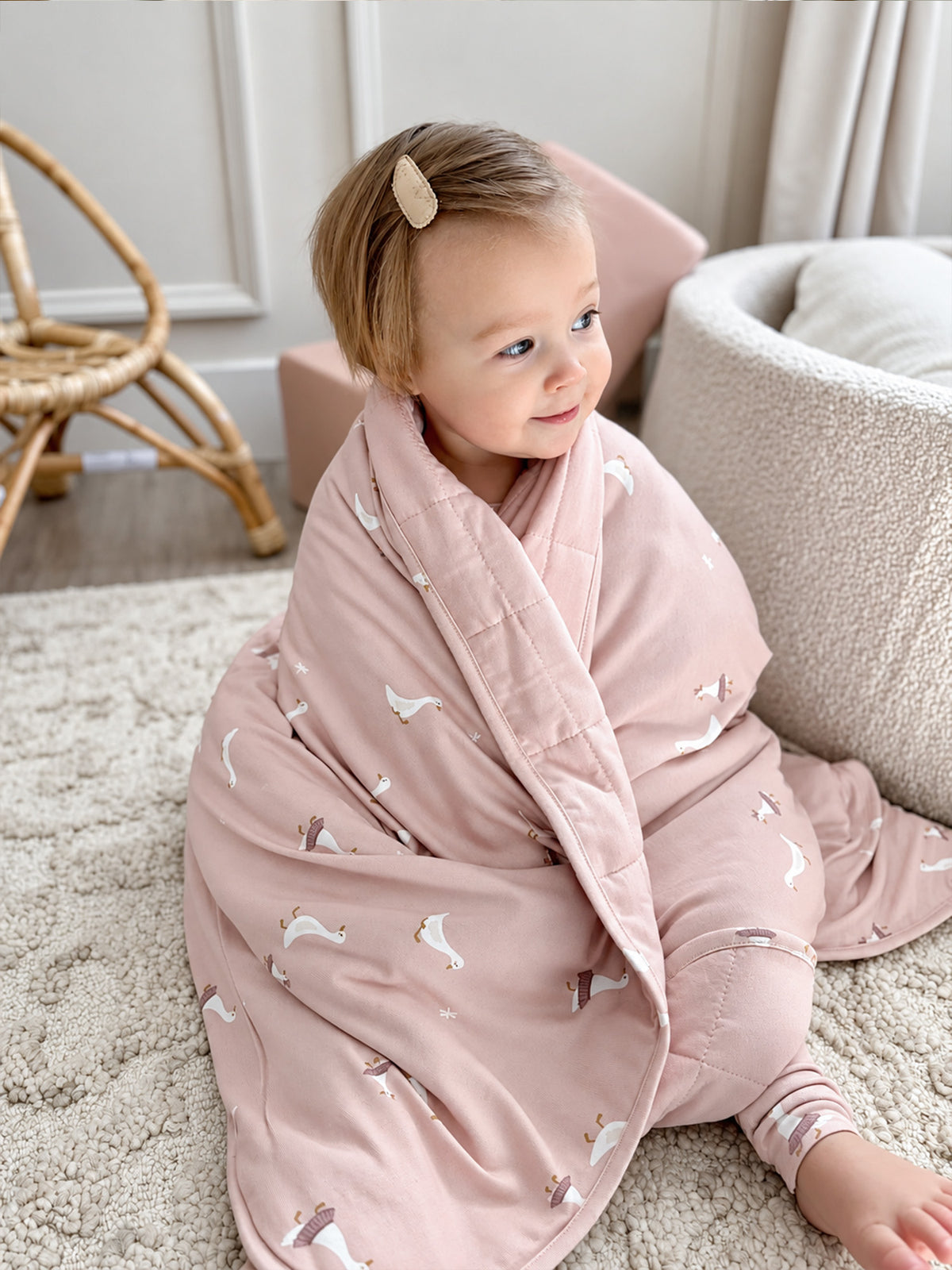 Dusty pink goose-print cloud blanket with wrap drape, child seated
