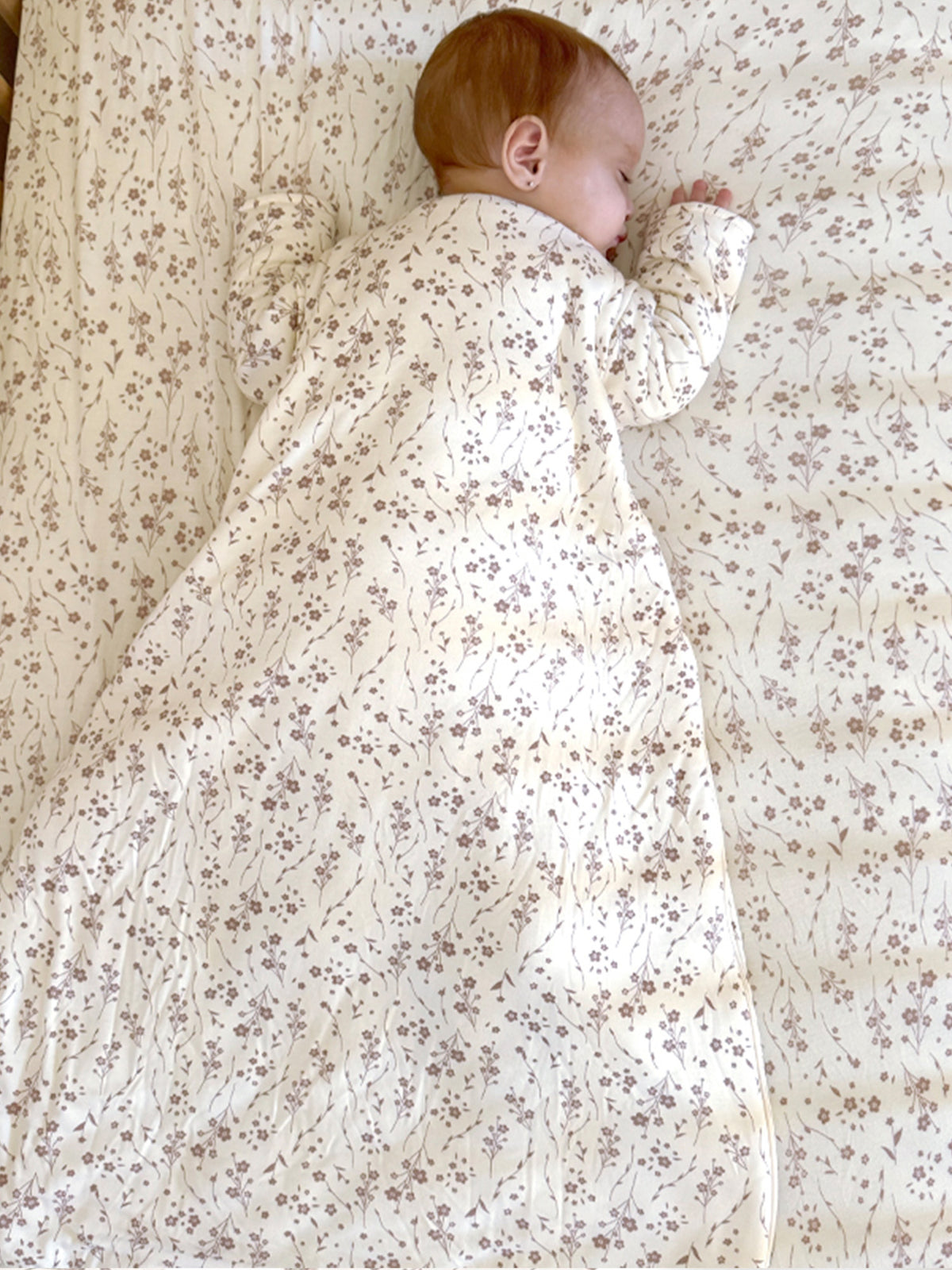 Cream long-sleeve sleep sack with small floral print, baby wearing with back turned