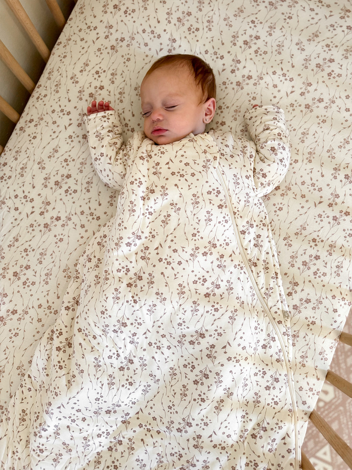 Cream floral long-sleeve sleep sack, baby lying with hands near the neckline