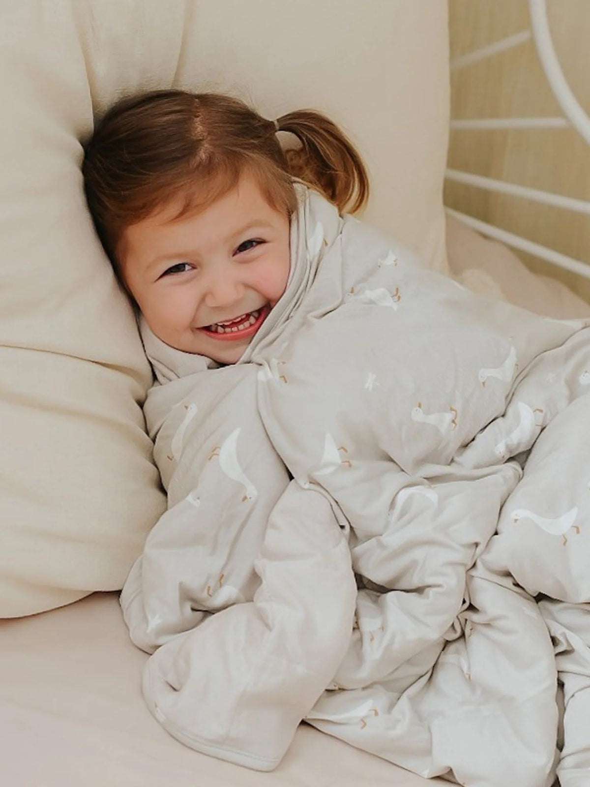 Goose-print cloud blanket, light cream with small geese pattern, wrapped around child
