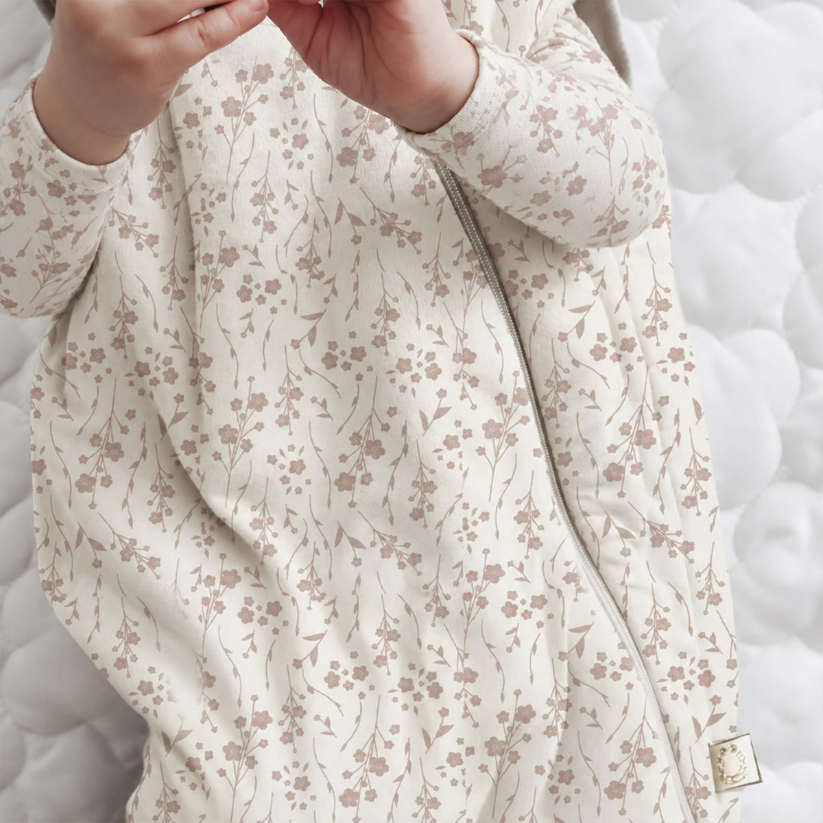 Beige floral sleep sack close-up showing long zipper and stitched trim