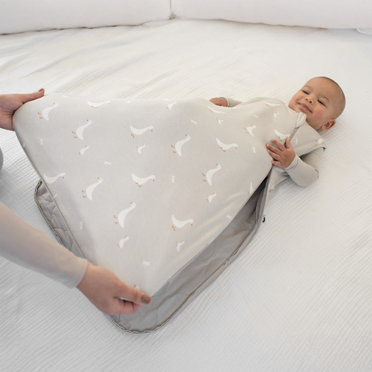 1.0 TOG goose print sleep sack, light gray; baby lying down wearing it