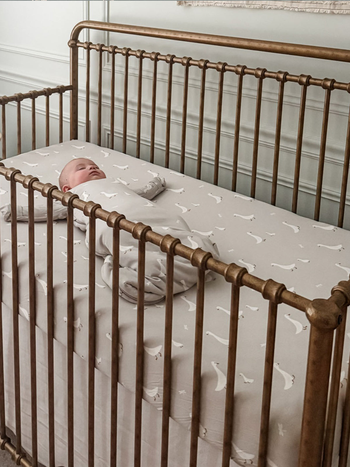 Crib sheet with white goose print laid across a crib mattress surface