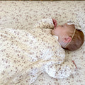 Cream floral long-sleeve sleep sack, baby lying on side with hands tucked