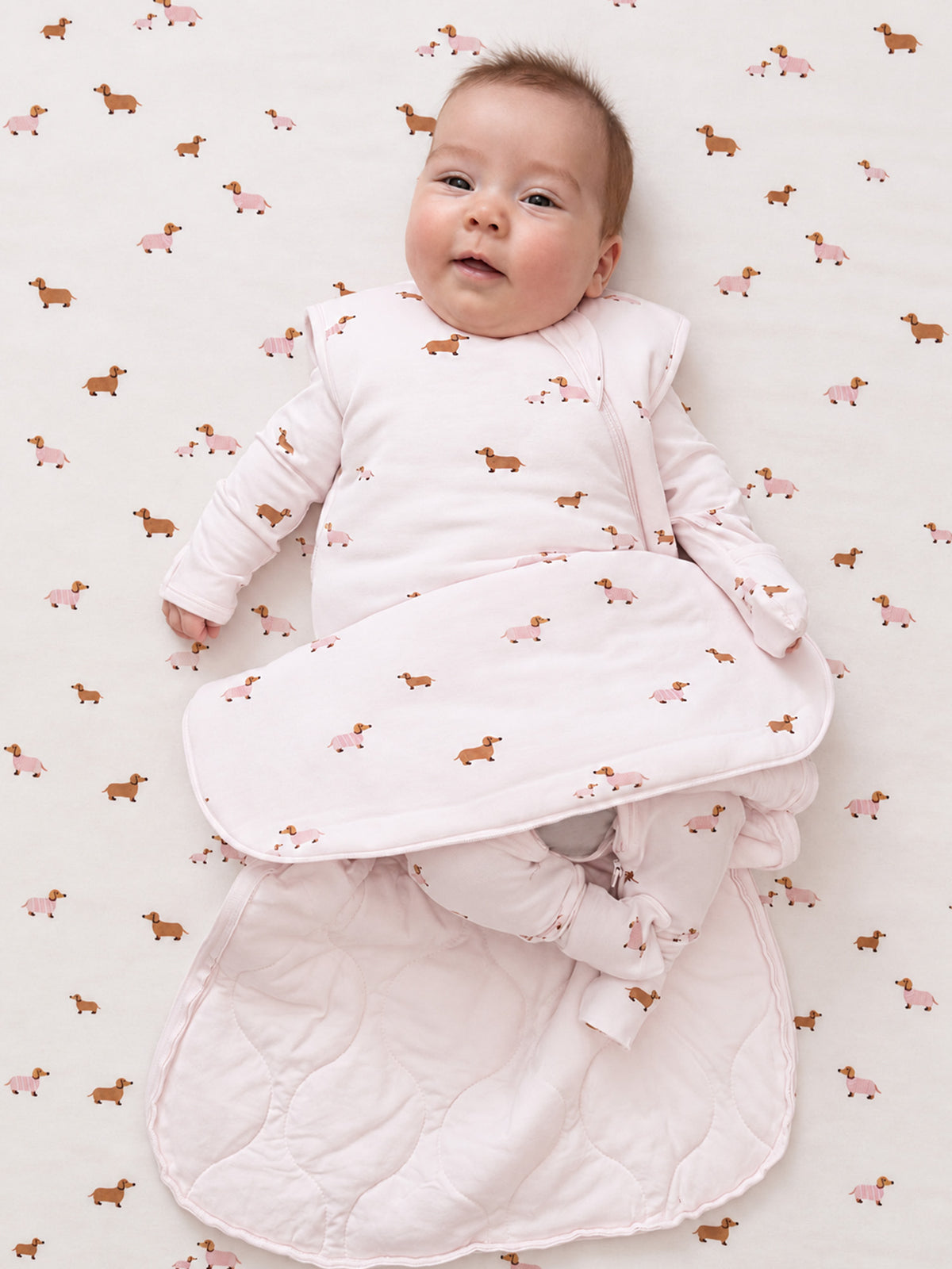 Dog-print infant swaddle sleep sack with open arms and padded wrap, pink zipper