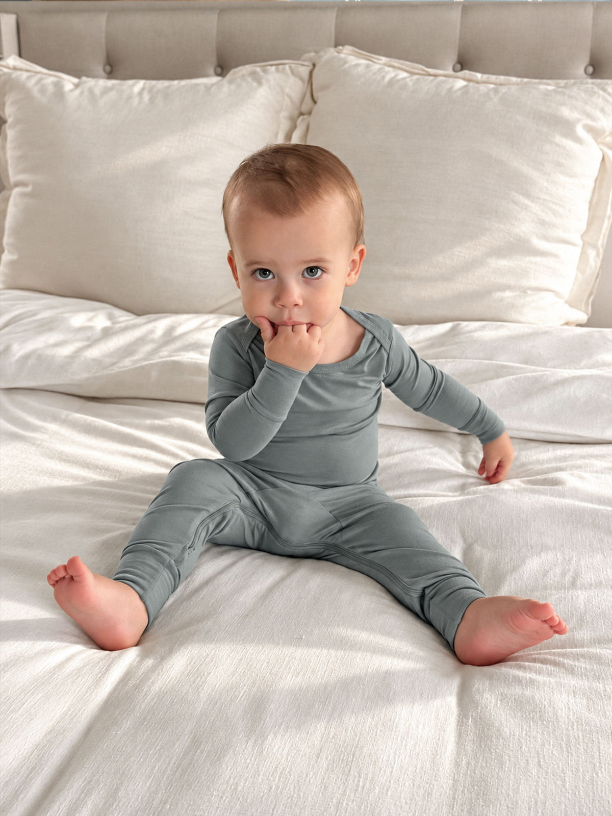 Light blue-green convertible footed pajamas with long sleeves, baby lying on sofa