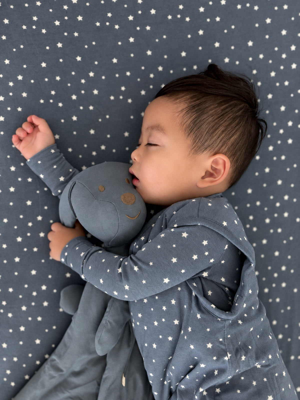 Navy crib sheet with scattered white star pattern, corner visible under baby