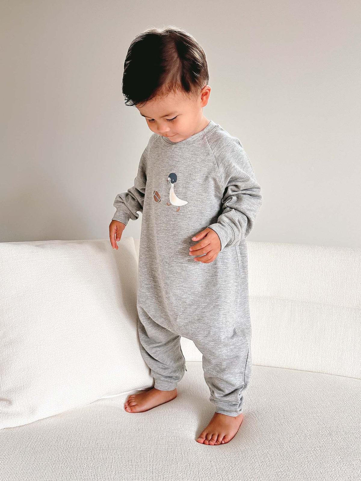 Gray fleece jumpsuit with long sleeves, cuffed legs, and goose applique on chest.