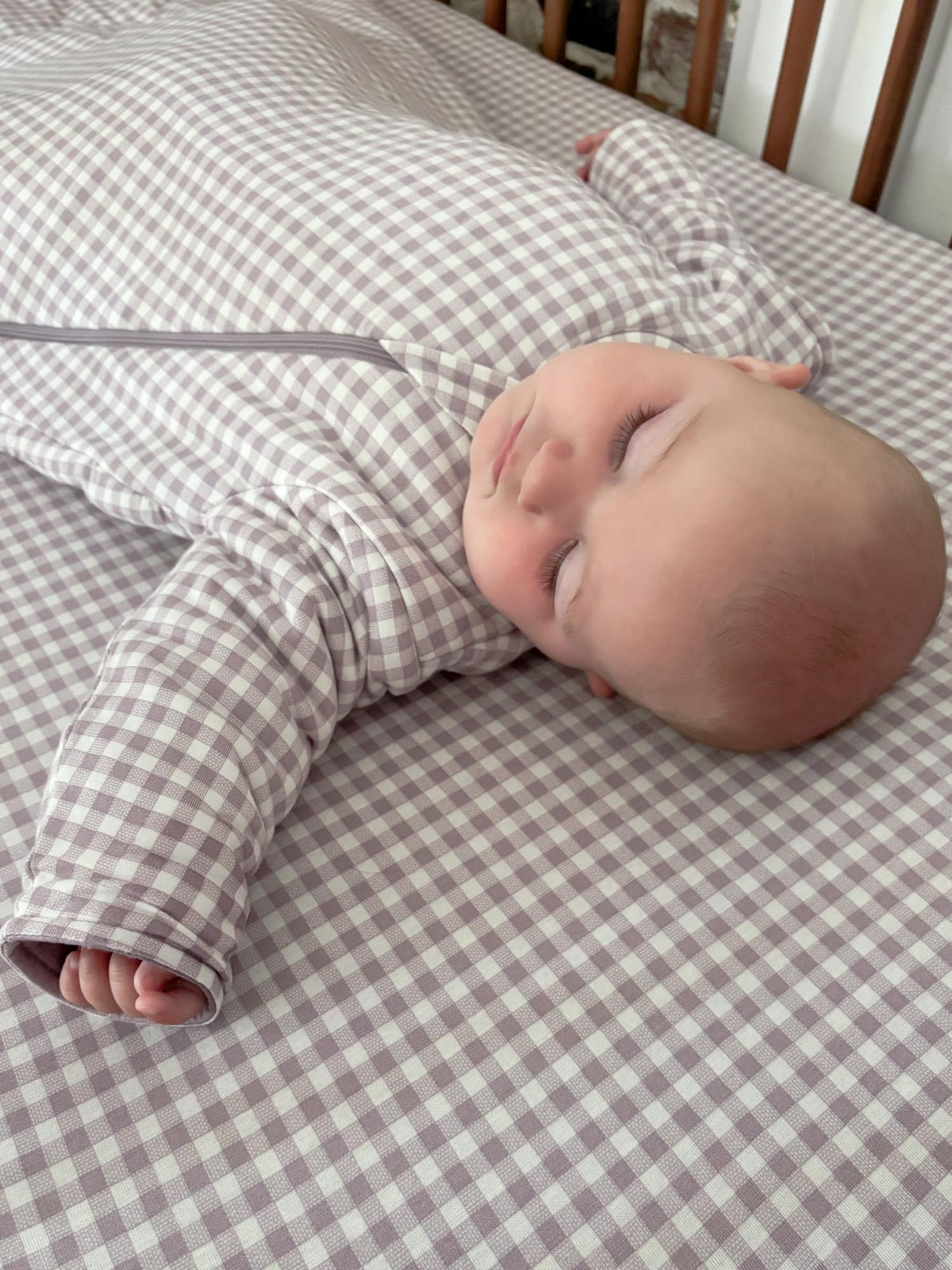 Checkered long-sleeve sleep sack on a sleeping baby, with folded hand openings.