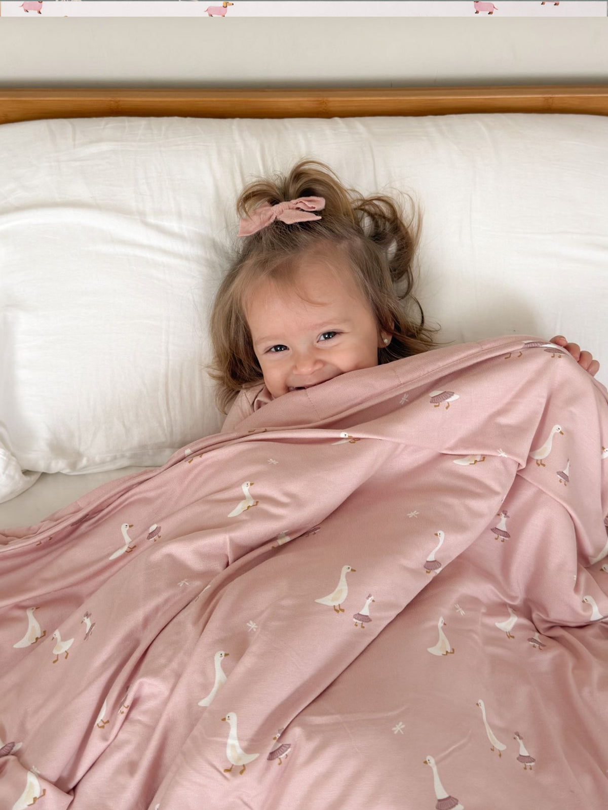 Goose-print cloud blanket in dusty pink, wrapped around a child