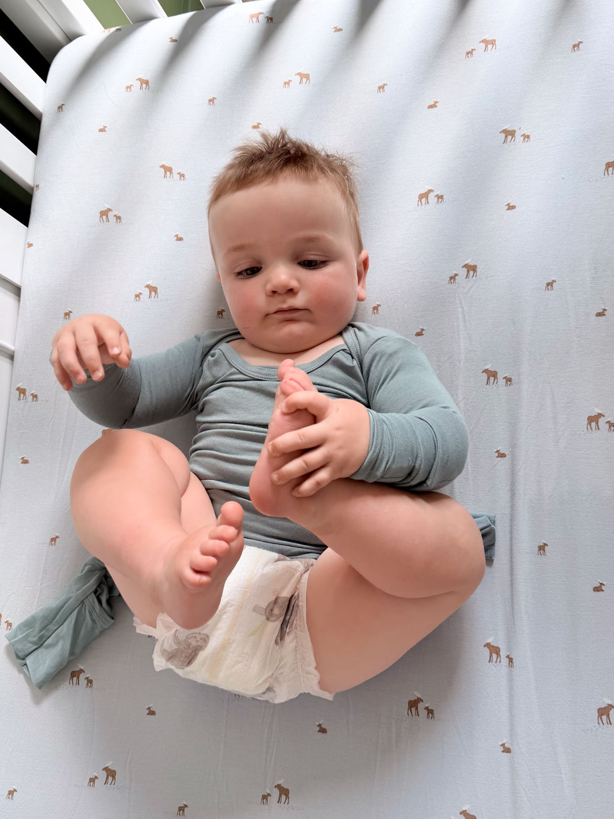 Light blue-green long-sleeve convertible pajamas on baby, close-up of torso and hands
