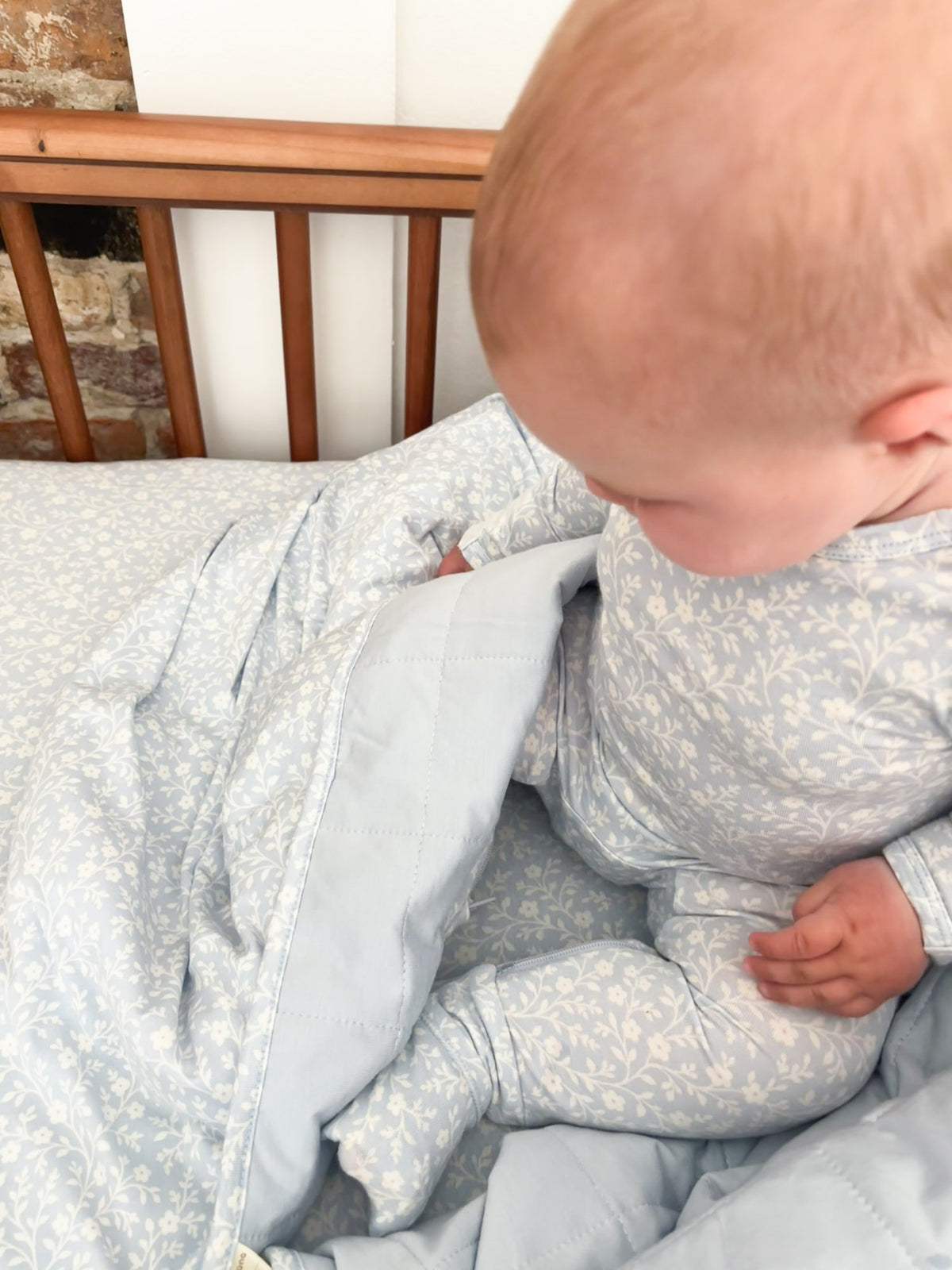 Light blue floral baby blanket with hood and open front, close-up over baby legs