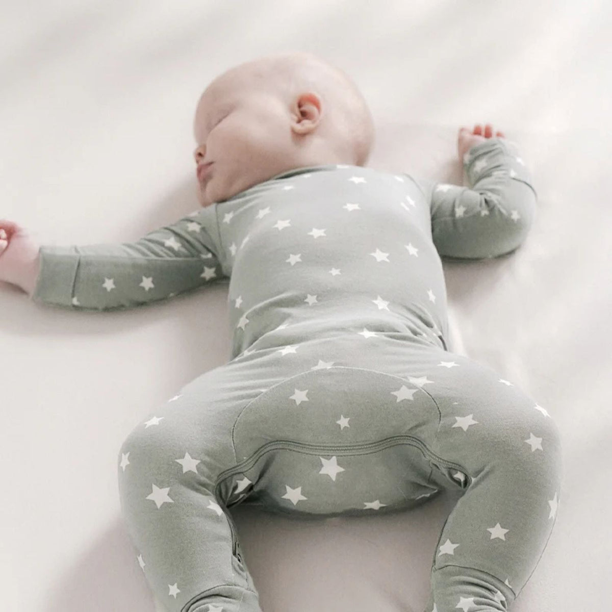 Sage green baby romper with long sleeves and white star print, rear view