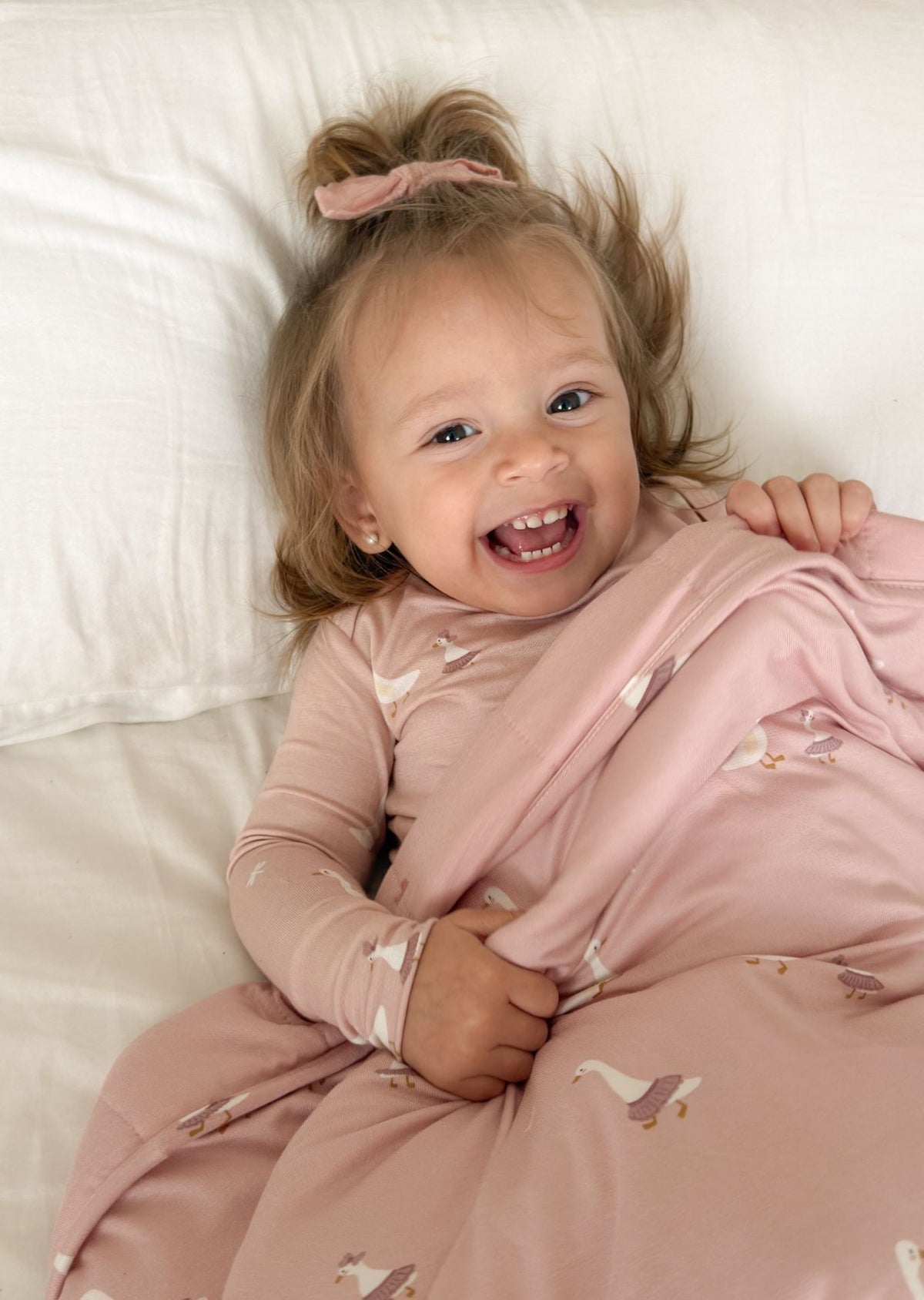 Pink printed twin blanket with goose motifs, draped over a baby